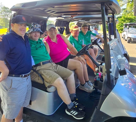 Five people in golf carts pose for picture