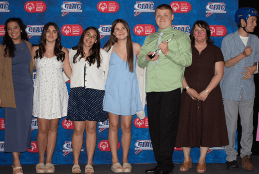 Group of athletes and Unified Sports partners pose for picture with award