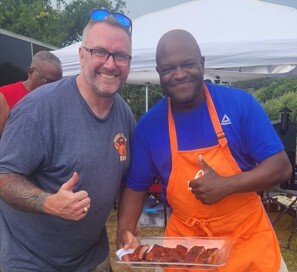 Two men give thumbs up holding tray of meat