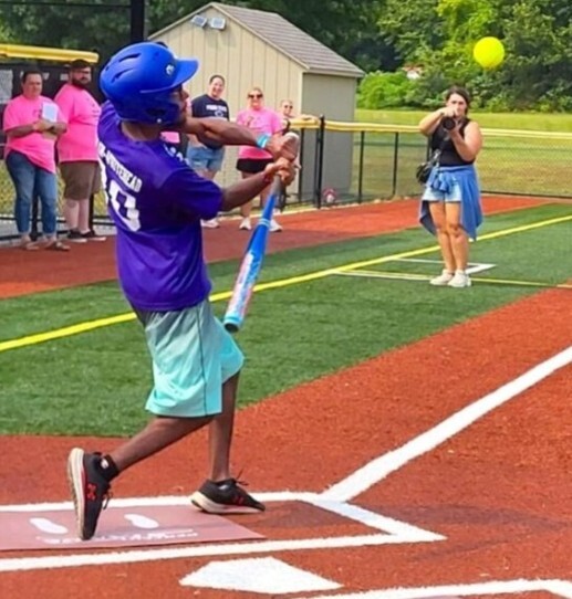 Softball player swings bat at softball