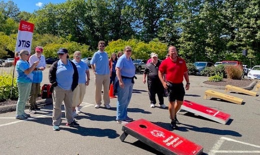 Group of people standing by cornhole boards